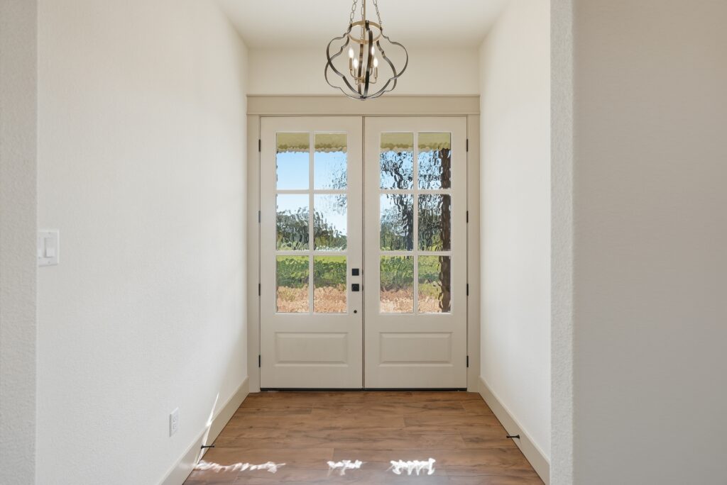 Modern farmhouse entry with wood beams and glass front doors