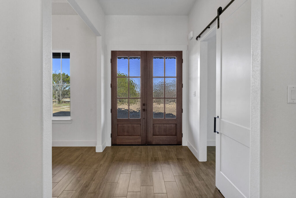 Modern farmhouse entryway with wood double doors and bright interior finishes